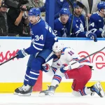 Oct 19, 2024; Toronto, Ontario, CAN; New York Rangers center Vincent Trocheck (16) battles along the boards with Toronto Maple Leafs center Auston Matthews (34) during the second period at Scotiabank Arena.
