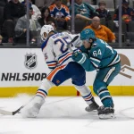 Dec 28, 2023; San Jose, California, USA; Edmonton Oilers defenseman Darnell Nurse (25) controls the puck against San Jose Sharks center Mikael Granlund (64) during the second period at SAP Center at San Jose. Mandatory Credit: Neville E. Guard-Imagn Images