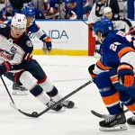 Nov 2, 2025; Elmont, New York, USA; Columbus Blue Jackets center Adam Fantilli (19) skates with the puck defended by New York Islanders defenseman Alexander Romanov (28) during the second period at UBS Arena.