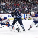 Apr 13, 2025; Winnipeg, Manitoba, CAN; Winnipeg Jets right wing Nino Niederreiter (62) is checked by Edmonton Oilers defenseman Ty Emberson (49) and Oilers right wing Vasily Podkolzin (92) in the second period at Canada Life Centre. Mandatory Credit: James Carey Lauder-Imagn Images