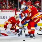 Mar 18, 2026; Calgary, Alberta, CAN; St. Louis Blues defenseman Philip Broberg (6) and Calgary Flames defenseman Zach Whitecloud (28) battle for the puck in front of Calgary Flames goaltender Devin Cooley (1) during the third period at Scotiabank Saddledome.