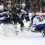 Jan 15, 2026; Saint Paul, Minnesota, USA; Minnesota Wild center Yakov Trenin (13) and Winnipeg Jets center Cole Perfetti (91) compete for the puck as goaltender Connor Hellebuyck (37) defend his net during the first period at Grand Casino Arena.