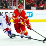 22 octobre 2025; Calgary, Alberta, Canada; Le centre des Flames de Calgary, Morgan Frost (16), et le défenseur des Canadiens de Montréal, Mike Matheson (8), se disputent la rondelle durant la deuxième période au Scotiabank Saddledome.
