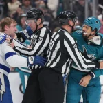 Jan 3, 2026; San Jose, California, USA; Tampa Bay Lightning defenseman J.J. Moser (left) and San Jose Sharks right wing Ryan Reaves (75) are restrained by linesmen Ryan Gibbons (58) and Travis Toomey (90) after a fight during the second period at SAP Center at San Jose.