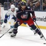 Jan 15, 2026; Columbus, Ohio, USA; Columbus Blue Jackets right wing Kirill Marchenko (86) pickls up a loose puck as Vancouver Canucks defenseman Tyler Myers (57) defends during the second period at Nationwide Arena.
