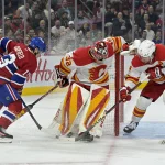 Nov 5, 2024; Montreal, Quebec, CAN; Calgary Flames goalie Dustin Wolf (32) loses the puck in his skates and Montreal Canadiens forward Cole Caufield (13) attempts to dig it out during the second period at the Bell Centre.