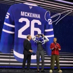 Jun 26, 2026; Buffalo, New York, USA; Gavin McKenna puts on a sweater beside NHL commissioner Gary Bettman and singer Justin Bieber after being selected with the first pick in the first round of the 2026 NHL Draft by the Toronto Maple Leafs at KeyBank Center.