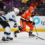22 septembre 2025 ; Anaheim, Californie, États-Unis ; l\'ailier droit des Ducks d\'Anaheim, Beckett Sennecke (45), manie le palet face au défenseur du Mammoth de l\'Utah, Maksymilian Szuber (55), durant la deuxième période au Honda Center.