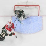 Jan 22, 2026; Saint Paul, Minnesota, USA; Minnesota Wild goalie Filip Gustavsson (32) makes a save on Detroit Red Wings forward Dylan Larkin (71) as defensemen Quinn Hughes (43) back checks in overtime at Grand Casino Arena.