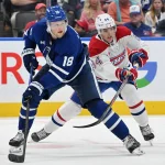 26 septembre 2024; Toronto, Ontario, Canada; L'attaquant des Maple Leafs de Toronto, Steven Lorentz (18), cherche une passe devant le défenseur des Canadiens de Montréal, David Reinbacher (64), en troisième période à la Scotiabank Arena.