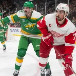 Dec 27, 2023; Saint Paul, Minnesota, USA; Minnesota Wild defenseman Jake Middleton (5) and Detroit Red Wings center Dylan Larkin (71) look for the puck in the third period at Xcel Energy Center. Mandatory Credit: Matt Blewett-USA TODAY Sports