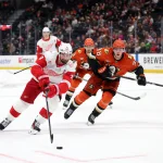 Oct 31, 2025; Anaheim, California, USA; Detroit Red Wings center Dylan Larkin (71) skates with the puck past Anaheim Ducks defenseman Pavel Mintyukov (98) during the third period at Honda Center. Mandatory Credit: Kiyoshi Mio-Imagn Images