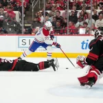 29 mai 2026 ; Raleigh, Caroline du Nord, États-Unis ; Kirby Dach (77), centre des Canadiens de Montréal, joue la rondelle face au défenseur Alexander Nikishin (21) et au gardien Frederik Andersen (31) des Hurricanes de la Caroline, lors du cinquième match de la finale de l'Association de l'Est des séries éliminatoires de la Coupe Stanley 2026, durant la deuxième période au Lenovo Center.