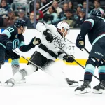 Apr 13, 2026; Seattle, Washington, USA; Los Angeles Kings forward Anze Kopitar (11) is tripped by forward Eeli Tolvanen (20) during the first period at Climate Pledge Arena. Mandatory Credit: Stephen Brashear-Imagn Images