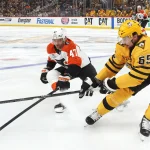 Apr 20, 2026; Pittsburgh, Pennsylvania, USA; Pittsburgh Penguins defenseman Erik Karlsson (65) clears the puck past Philadelphia Flyers defenseman Noah Juulsen (47) during the second period in game two of the first round of the 2026 Stanley Cup Playoffs at PPG Paints Arena.