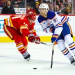 Dec 27, 2025; Calgary, Alberta, CAN; Edmonton Oilers center Connor McDavid (97) and Calgary Flames left wing Jonathan Huberdeau (10) battle for the puck during the first period at Scotiabank Saddledome. Mandatory Credit: Sergei Belski-Imagn Images