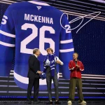 Jun 26, 2026; Buffalo, New York, USA; Gavin McKenna puts on a sweater beside NHL commissioner Gary Bettman and singer Justin Bieber after being selected with the first pick in the first round of the 2026 NHL Draft by the Toronto Maple Leafs at KeyBank Center.