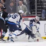 Jan 20, 2025; Salt Lake City, Utah, USA; Winnipeg Jets goaltender Connor Hellebuyck (37) blocks a shot while center Mark Scheifele (55) and Utah Hockey Club right wing Josh Doan (91) look for a rebound during the first period at Delta Center.