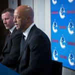 Jun 4, 2026; Vancouver, BC, CANADA; General manager Ryan Johnson listens to Manny Malhotra speak during press conference where the Vancouver Canucks introduce Malhotra as their new head coach during a press conference at Rogers Arena.