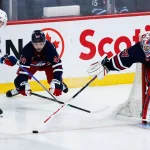 Mar 12, 2026; Winnipeg, Manitoba, CAN; Winnipeg Jets goalie Connor Hellebuyck (37) pokes the puck away from New York Rangers forward Alexis Lafreniere (13) and Winnipeg Jets defenseman Josh Morrissey (44) during the second period at Canada Life Centre.