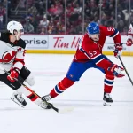 Apr 5, 2026; Montreal, Quebec, CAN; Montreal Canadiens defenseman Noah Dobson (53) plays the puck against New Jersey Devils center Jack Hughes (86) during the third period at Bell Centre.