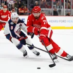 Apr 7, 2026; Detroit, Michigan, USA; Detroit Red Wings center Dylan Larkin (71) skates with the puck in overtime defended by Columbus Blue Jackets defenseman Zach Werenski (8) at Little Caesars Arena.