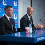 Jun 4, 2026; Vancouver, BC, CANADA; General manager Ryan Johnson listens to Manny Malhotra speak during press conference where the Vancouver Canucks introduce Malhotra as their new head coach during a press conference at Rogers Arena.