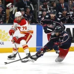Jan 13, 2026; Columbus, Ohio, USA; Calgary Flames left wing Ryan Lomberg (70) sweeps the puck off the stick of Columbus Blue Jackets right wing Kirill Marchenko (86) during the second period at Nationwide Arena.