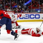Mar 18, 2025; Washington, District of Columbia, USA; Washington Capitals center Nic Dowd (26) shoots the puck against Detroit Red Wings defenseman Justin Holl (3) during the first period at Capital One Arena.