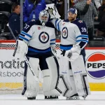 Apr 13, 2024; Denver, Colorado, USA; Winnipeg Jets goaltender Connor Hellebuyck (37) reacts with goaltender Laurent Brossoit (39) after the game against the Colorado Avalanche at Ball Arena.