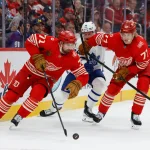 Dec 28, 2025; Detroit, Michigan, USA; Detroit Red Wings center Dylan Larkin (71) skates with the puck chased by Toronto Maple Leafs center Bobby McMann (74) and defenseman Simon Edvinsson (77) in the first period at Little Caesars Arena.