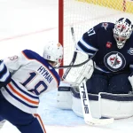 Jan 8, 2026; Winnipeg, Manitoba, CAN; Edmonton Oilers left wing Zach Hyman (18) scores on Winnipeg Jets goaltender Connor Hellebuyck (37) in the third period at Canada Life Centre.