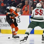 Oct 18, 2025; Philadelphia, Pennsylvania, USA; Philadelphia Flyers center Christian Dvorak (22) passes the puck against Minnesota Wild defenseman David Jiricek (55) during the first period at Wells Fargo Center.