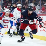 18 décembre 2023; Winnipeg, Manitoba, Canada; David Gustafsson (19), attaquant des Jets de Winnipeg, tente d'échapper à Jesse Ylonen (56), attaquant des Canadiens de Montréal, durant la deuxième période au Canada Life Centre.