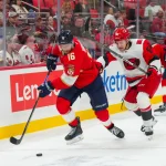 Sep 22, 2026; Raleigh, North Carolina, USA; Florida Panthers center Aleksander Barkov (16) skates with the puck past Carolina Hurricanes defensemen Joel Nystrom (64) during the overtime at Lenovo Center.