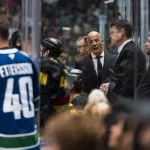 vOct 3, 2026; Vancouver, British Columbia, CAN; Vancouver Canucks head coach Manny Malhotra on the bench against the Calgary Flames in the second period at Rogers Arena. Mandatory Credit: Bob Frid-Imagn Images
