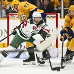 Feb 4, 2026; Nashville, Tennessee, USA; Minnesota Wild defenseman Jared Spurgeon (46) and Nashville Predators left wing Michael Bunting (58) battle for the puck during the first period at Bridgestone Arena.
