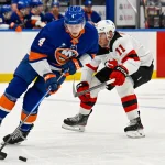 Jan 6, 2026; Elmont, New York, USA; New York Islanders defenseman Cole McWard (4) plays the puck defended by New Jersey Devils right wing Stefan Noesen (11) during the first period at UBS Arena.