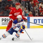 Oct 19, 2025; Detroit, Michigan, USA; Edmonton Oilers center Matt Savoie (22) vies for position with Detroit Red Wings defenseman Simon Edvinsson (77) in the first period at Little Caesars Arena.
