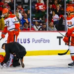Oct 10, 2026; Calgary, Alberta, CAN; Anaheim Ducks center Ryan Poehling (25) gets help of the ice after his collision with the net of the Calgary Flames goaltender Dustin Wolf (32) during the third period at Scotiabank Saddledome.