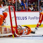 Oct 10, 2026; Calgary, Alberta, CAN; Anaheim Ducks center Ryan Poehling (25) crashes into the net of the Calgary Flames goaltender Dustin Wolf (32) during the third period at Scotiabank Saddledome. Mandatory Credit: Sergei Belski-Imagn Images
