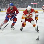 Nov 5, 2024; Montreal, Quebec, CAN; Calgary Flames forward Matt Coronato (27) plays the puck and Montreal Canadiens forward Kirby Dach (77) defends during the first period at the Bell Centre.