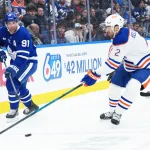 Dec 13, 2025; Toronto, Ontario, CAN; Toronto Maple Leafs center John Tavares (91) battles for the puck behind the net with Edmonton Oilers defenseman Evan Bouchard (2) during the first period at Scotiabank Arena.