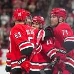 Oct 8, 2026; Raleigh, North Carolina, USA; Carolina Hurricanes center Logan Stankoven (22) celebrates his hat trick goal with left wing Taylor Hall (71) defenseman Sean Walker (26) and right wing Jackson Blake (53) against the Vancouver Canucks during the third period at Lenovo Center.
