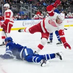 Oct 2, 2025; Toronto, Ontario, CAN; Toronto Maple Leafs center Auston Matthews (34) battles with Detroit Red Wings defenseman Simon Edvinsson (77) during the first period at Scotiabank Arena.