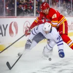 Feb 2, 2026; Calgary, Alberta, CAN; Toronto Maple Leafs center Bobby McMann (74) and Calgary Flames defenseman Zach Whitecloud (28) battle for the puck during the first period at Scotiabank Saddledome.