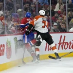 Apr 5, 2025; Montreal, Quebec, CAN; Philadelphia Flyers forward Owen Tippett (74) checks Montreal Canadiens forward Emil Heineman (51) into the boards during the second period at the Bell Centre.
