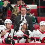 Feb 3, 2026; Raleigh, North Carolina, USA; Ottawa Senators head coach Travis Green looks on from behind the players bench against the Carolina Hurricanes during the third period at Lenovo Center.
