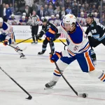 Oct 17, 2026; Salt Lake City, Utah, USA; Edmonton Oilers left wing Isaac Howard (53) takes a shot on goal around Utah Mammoth defenseman MacKenzie Weegar (52) during first period at Delta Center.