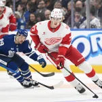 Jan 21, 2026; Toronto, Ontario, CAN; Detroit Red Wings defenseman Simon Edvinsson (77) skates the puck away from Toronto Maple Leafs forward Nick Robertson (89) in the first period at Scotiabank Arena.